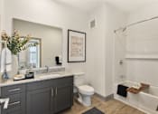 Thumbnail 4 of 27 - Model apartment bathroom at Montage West Lafayette featuring granite countertops, modern vanity cabinetry, framed mirror, and contemporary finishes.