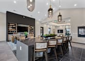 Thumbnail 8 of 27 - Community bar and lounge area with oversized island seating, pendant lighting, built-in shelving, and modern finishes at Montage apartment community