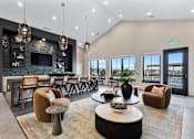 Thumbnail 14 of 27 - Spacious resident lounge with bar seating, pendant lighting, modern fireplace wall, and pool views at Montage apartment community