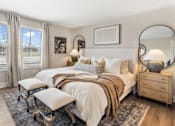 Thumbnail 31 of 45 - Spacious primary bedroom in single-family rental home at Mural Lewis Center featuring large windows, plush bedding, neutral tones, wall art, and soft carpeting