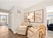 Thumbnail 24 of 45 - Inviting seating area in single-family rental home at Mural Lewis Center featuring neutral tones, accent chairs, wall art, wood-style flooring, and warm natural light