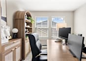 Thumbnail 25 of 45 - Modern home office at Mural Lewis Center featuring a large window with natural light, wood desk, computer setup, ergonomic chair, and built-in shelving for storage