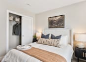 Thumbnail 29 of 45 - Comfortable bedroom in single-family rental home at Mural Lewis Center featuring plush bedding, neutral decor, bedside lighting, wall art, and walk-in closet with sliding door