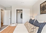 Thumbnail 27 of 45 - Clean and modern apartment bedroom at Mural Lewis Center featuring neutral tones, ceiling fan, walk-in closet access, soft carpeting, and contemporary decor