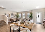 Thumbnail 16 of 45 - Bright open-concept dining and living space at Mural Lewis Center featuring wood-style flooring, large windows, modern dining table, neutral decor, and seamless flow into the kitchen and living room