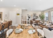 Thumbnail 18 of 45 - Bright open-concept dining and living space in single-family rental home at Mural Lewis Center featuring wood-style flooring, modern dining table, neutral decor, and seamless flow into kitchen and living areas