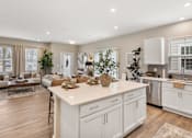 Thumbnail 4 of 45 - Modern apartment kitchen at Mural Lewis Center featuring large island with quartz countertops, white cabinetry, stainless steel appliances, wood-style flooring, and open-concept design