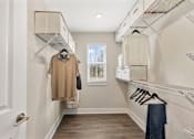 Thumbnail 30 of 45 - Large walk-in closet at Mural Lewis Center featuring built-in shelving, hanging racks, wood-style flooring, and organized storage space with natural light