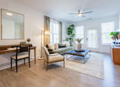 Thumbnail 13 of 53 - Apartment living room with work-from-home desk, natural lighting, and ceiling fan