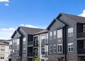 Thumbnail 37 of 53 - Apartment buildings with balconies and a clear blue sky above.