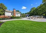 Thumbnail 9 of 49 - A house with a white garage door is surrounded by a green lawn and trees.