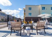 Thumbnail 33 of 36 - a patio with tables and chairs and a building in the background at The Century at Purdue Research Park-Student, West Lafayette, IN