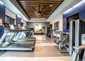 Thumbnail 25 of 36 - a gym with cardio equipment and a ceiling fan at The Century at Purdue Research Park-Student, West Lafayette, IN