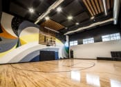 Thumbnail 23 of 36 - a basketball court in a gym with a colorful wall and wood floors at The Century at Purdue Research Park-Student, West Lafayette