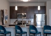 Thumbnail 3 of 36 - a kitchen with four blue chairs in front of a counter topat The Century at Purdue Research Park-Student, West Lafayette, IN 47906