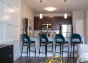 Thumbnail 1 of 36 - a kitchen with bar stools and a kitchen island with stools at The Century at Purdue Research Park-Student, West Lafayette Indiana