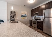 Thumbnail 4 of 36 - a kitchen with stainless steel appliances and granite counter tops at The Century at Purdue Research Park-Student, West Lafayette, IN 47906
