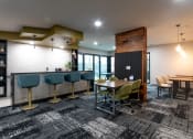Thumbnail 4 of 34 - a lounge area with tables and chairs and a bar with stools at 310 at Nulu Apartments-Student, Louisville, 40202