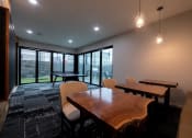 Thumbnail 9 of 34 - a conference room with a wooden table and chairs and large windows at 310 at Nulu Apartments-Student, Louisville, KY 40202
