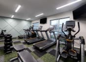 Thumbnail 11 of 34 - a gym with various pieces of exercise equipment and a window at 310 at Nulu Apartments-Student, Louisville Kentucky