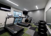 Thumbnail 12 of 34 - a gym with treadmills and other exercise equipment in a building at 310 at Nulu Apartments-Student, Louisville, KY 40202