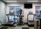 Thumbnail 17 of 34 - a gym with four treadmills and a tv on the wall at 310 at Nulu Apartments-Student, Louisville Kentucky