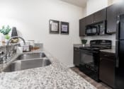 Thumbnail 20 of 34 - a kitchen with granite counter tops and black appliances at 310 at Nulu Apartments-Student, Kentucky, 40202
