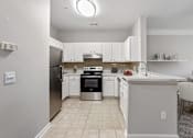 Thumbnail 6 of 33 - A kitchen with white cabinets and a black stove top oven at Village at Almand Creek, Conyers, GA 30094