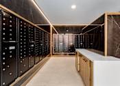 Thumbnail 21 of 38 - Organized mailroom at Portrait Midtown featuring modern black secure mailboxes and a sleek service counter.