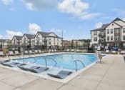 Thumbnail 17 of 38 - a swimming pool with lounge chairs in front of an apartment building