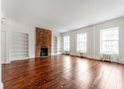 Thumbnail 16 of 18 - an empty living room with hardwood floors and a brick fireplace