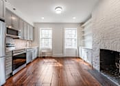 Thumbnail 7 of 18 - a kitchen with a large brick fireplace and hardwood floors
