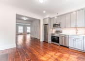 Thumbnail 9 of 18 - a kitchen and living room with white cabinets and wood floors