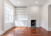Thumbnail 8 of 18 - a living room with a brick fireplace and white walls