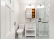Thumbnail 5 of 18 - a bathroom with white walls and a white toilet next to a walk in shower with a glass