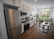 Thumbnail 1 of 22 - A modern kitchen with a stainless steel refrigerator and a dining table with chairs.