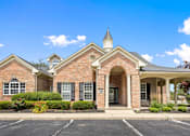 Thumbnail 48 of 65 - Welcoming leasing office with classic brick architecture, landscaped entrance, and covered porte cochère at Steeplechase at Shiloh Crossing Apartments in Avon, Indiana.