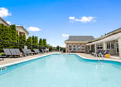 Thumbnail 55 of 65 - Resort-style outdoor swimming pool with spacious sundeck, lounge chairs, and the resident clubhouse at Steeplechase at Shiloh Crossing Apartments in Avon, Indiana.