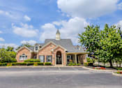 Thumbnail 47 of 65 - Beautifully landscaped leasing office and community entrance featuring classic brick architecture at Steeplechase at Shiloh Crossing Apartments in Avon, Indiana.