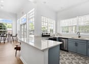 Thumbnail 61 of 65 - Modern resident clubhouse kitchen featuring quartz countertops, updated cabinetry, stainless steel appliances, and large windows overlooking the community at Steeplechase at Shiloh Crossing Apartments in Avon, Indiana.