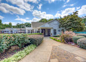 Thumbnail 43 of 49 - A white building with a brown roof is surrounded by green bushes and trees.
