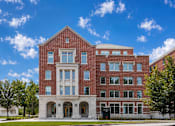 Thumbnail 2 of 58 - A red brick building with a white entrance and a tree in front.