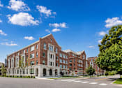 Thumbnail 7 of 58 - A large red brick building with white trim and a tree in front.