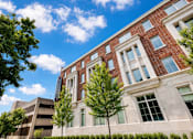 Thumbnail 6 of 58 - A red brick building with a parking garage behind it.