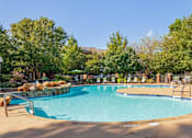 Thumbnail 3 of 7 - Resort-style swimming pool with waterfall feature, lush landscaping, and lounge seating at Village at Almand Creek apartments in Conyers, GA. Ideal for relaxation and outdoor enjoyment.