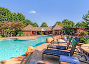 Thumbnail 4 of 7 - Resort-style swimming pool with lounge chairs, lush landscaping, and clubhouse at Village at Almand Creek apartments in Conyers, GA. Perfect for relaxation and outdoor living.