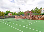Thumbnail 5 of 7 - Outdoor tennis court with scenic landscaping and community amenities at Village at Almand Creek apartments in Conyers, GA. Perfect for recreation and active living.