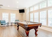 Thumbnail 7 of 7 - Stylish resident game room with a pool table, lounge seating, and large windows at Village at Almand Creek apartments in Conyers, GA. Perfect for socializing and relaxation.