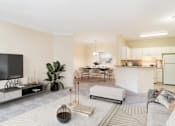 Thumbnail 1 of 7 - Spacious open-concept living room, dining area, and kitchen in an upscale apartment at Village at Almand Creek in Conyers, GA. Features modern furnishings, natural light, and elegant design.