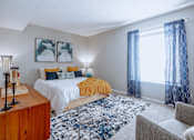 Thumbnail 20 of 38 - a bedroom with a bed and a window with blue curtains